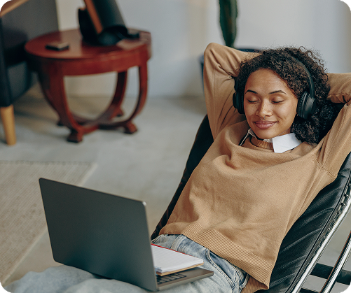 Smiling woman with headphones relaxing with laptop